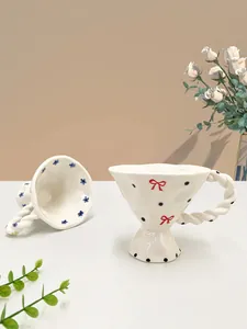 Detail of hand-pinched ceramic mug with floral patterns and braided handle in retro style