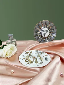 Gros plan de bijoux dorés sur un plateau en céramique à motif d'œil sur soie rose doux