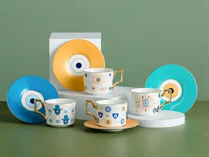 Dettaglio di tazzine da caffè in ceramica malocchio con manici dorati e piattini colorati