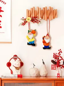 Detailed view of two Christmas gnome resin ornaments hanging with red strings on a wooden rack