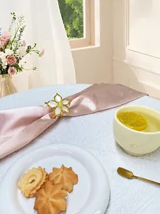 Dettaglio dell'elegante portatovagliolo a fiori bianchi e oro su seta rosa