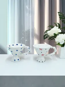 Detailed close-up of ceramic mugs with floral patterns, wavy rims and braided handles