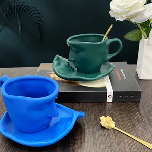 Artistic face relief ceramic coffee cup and saucer set with golden flower spoon