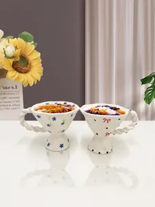 Detail of vintage floral ceramic goblets with twisted handles and elegant hand-painted patterns