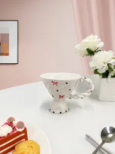 Detail of floral ceramic cup with hand-painted bows and unique twisted handle