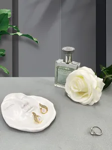 Artistic face-shaped tray showcasing elegant gold drop earrings and a classic silver ring
