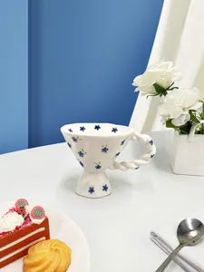 Detail of floral ceramic mug with blue patterns and a unique twisted handle for tea