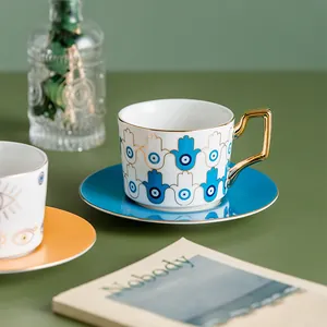 Dettaglio di tazza da caffè in ceramica bianca con piattino blu e motivo malocchio