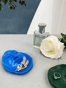 Close-up of golden pearl brooch and crystal ring on a blue face-shaped resin jewelry tray