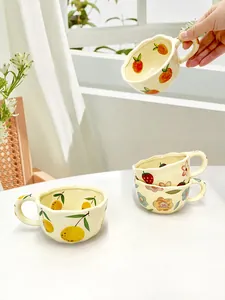 Detail of a handmade ceramic strawberry mug with wavy edges and thick round handle