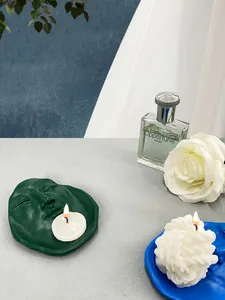 Artistic face relief trays in dark green and blue resin with burning white candles