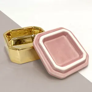 Macro di una scatola di gioielli in ceramica rosa con base dorata e coperchio a strati