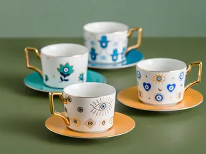 Dettaglio di tazzine da caffè in ceramica con motivi malocchio e manici quadrati dorati