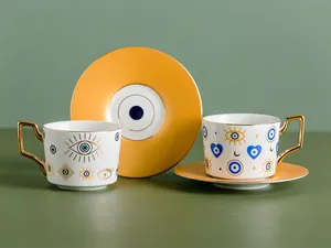 Dettaglio di tazzine da caffè in ceramica con motivi occhio blu e manici dorati geometrici