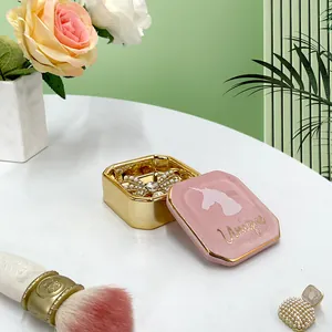 Dettaglio del portagioie in ceramica rosa con unicorno dorato e scritta Unique lucida