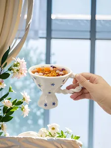 Detail of hand-painted floral ceramic goblet with unique twisted handle and dessert inside