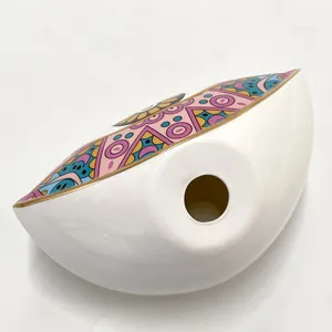 Detailed macro view of white ceramic Evil Eye ornament with gold gilded colorful painting