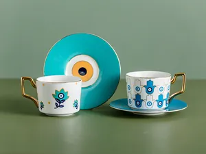 Dettagli del set da caffè in ceramica con manici dorati e motivi malocchio