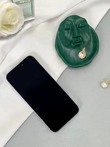 Detailed shot of golden flame earrings with white pearl and diamonds on a green face tray