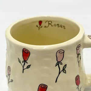 Detailed close-up of cream ceramic mug featuring hand-painted roses and textured finish