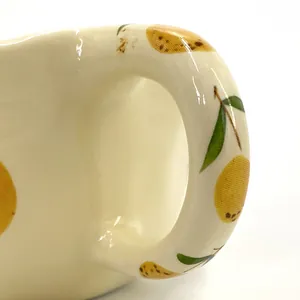 Detail of a handmade ceramic lemon mug with glossy finish and a smooth round handle