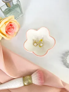 Dettaglio orecchini con perle dorate e zirconi su un vassoio decorativo in ceramica