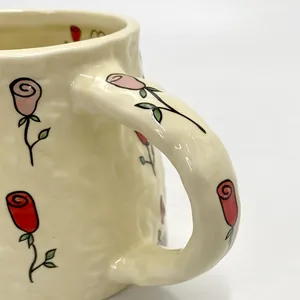 Detail of handmade ceramic mug with rose floral patterns and unique textured glaze