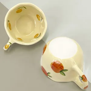 Top view of handmade ceramic mug with hand-painted fruit patterns and creamy glaze