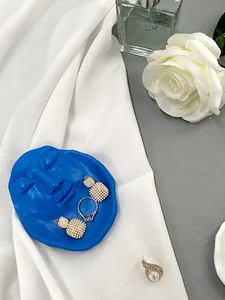 Close-up of a blue resin face-shaped jewelry tray with pearl earrings and a ring