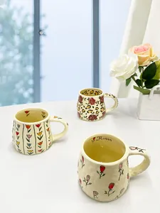 Detail of cream ceramic mug with hand-pinched texture and floral rose patterns