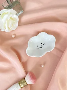 Elegante vassoio per gioielli in ceramica a nuvola bianca su sfondo di raso rosa