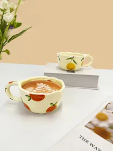 Detail of handmade ceramic orange pattern coffee cups with irregular wavy edges