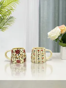 Detailed view of handmade ceramic mugs with rose, leopard, and tulip floral patterns