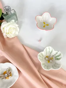 Dettaglio di vassoi per gioielli in ceramica a forma di fiore con orecchini di perle