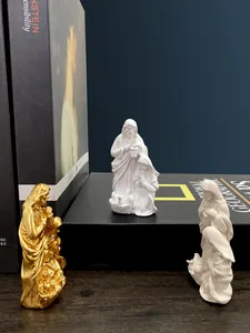 Detailed view of resin Holy Family figurines in gold and white on a bookshelf