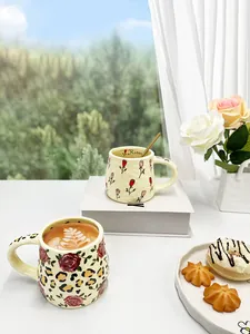 Macro shot of handmade ceramic mug with rose floral pattern and unique gold spoon