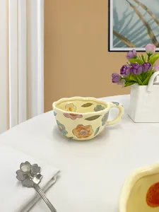 Detail of handmade floral ceramic mug with wavy rim and colorful hand-painted flowers
