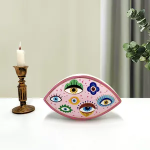 Close-up of pink ceramic evil eye decor with gold rim and artistic celestial patterns