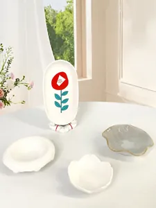 Vassoi per gioielli in ceramica e portacandele con motivi floreali su un tavolo bianco