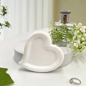 Close-up of a white heart-shaped resin jewelry tray with elegant rings and home decor
