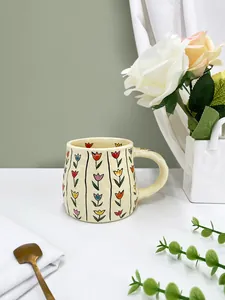 Close-up of handmade ceramic mug with colorful tulip patterns and textured finish
