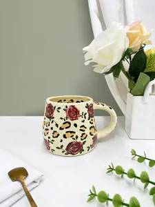 Close-up of handmade ceramic mug with red rose floral and leopard print pattern design