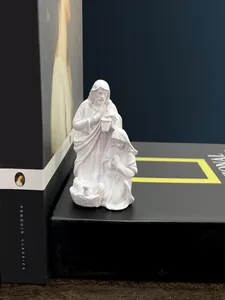 Detailed white resin sculpture of the Holy Family displayed on a vintage book stand