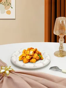 Close-up of a white ceramic plate with pink bows holding fried chicken on a dining table