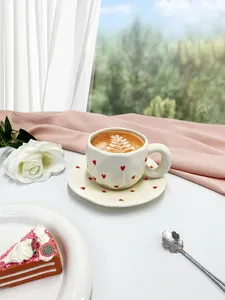 Close-up of heart-patterned ceramic coffee cup set on pink silk in bright natural light
