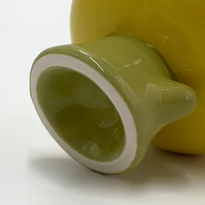 Détail macro du mug tulipe en céramique montrant le corps jaune et le pied vert