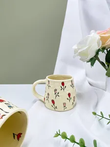Close-up of handmade ceramic mug with embossed rose floral pattern on creamy yellow glaze