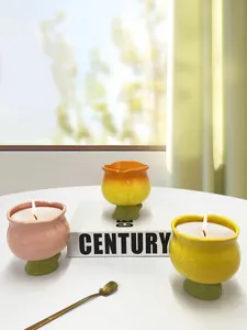 Trois bougies parfumées en forme de tulipe sur une table blanche minimaliste