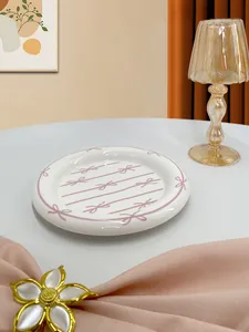 Detail of a ceramic dessert plate with pink bow patterns in a cozy scene setup