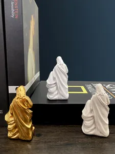 Three-piece family resin figurines in gold and white finish on a bookshelf